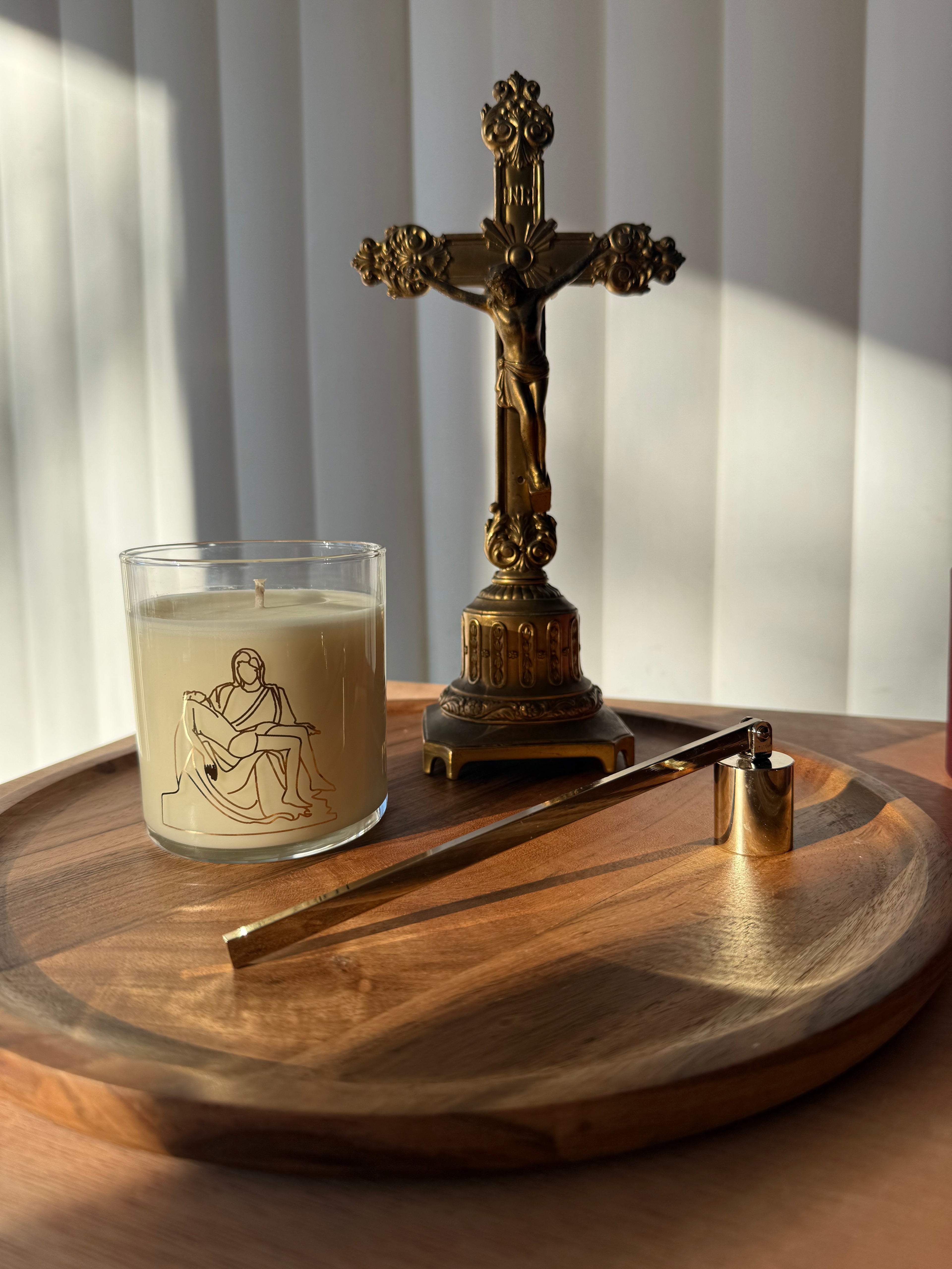 a round display tray with a candle, candle snuffer, and crucifix on top.