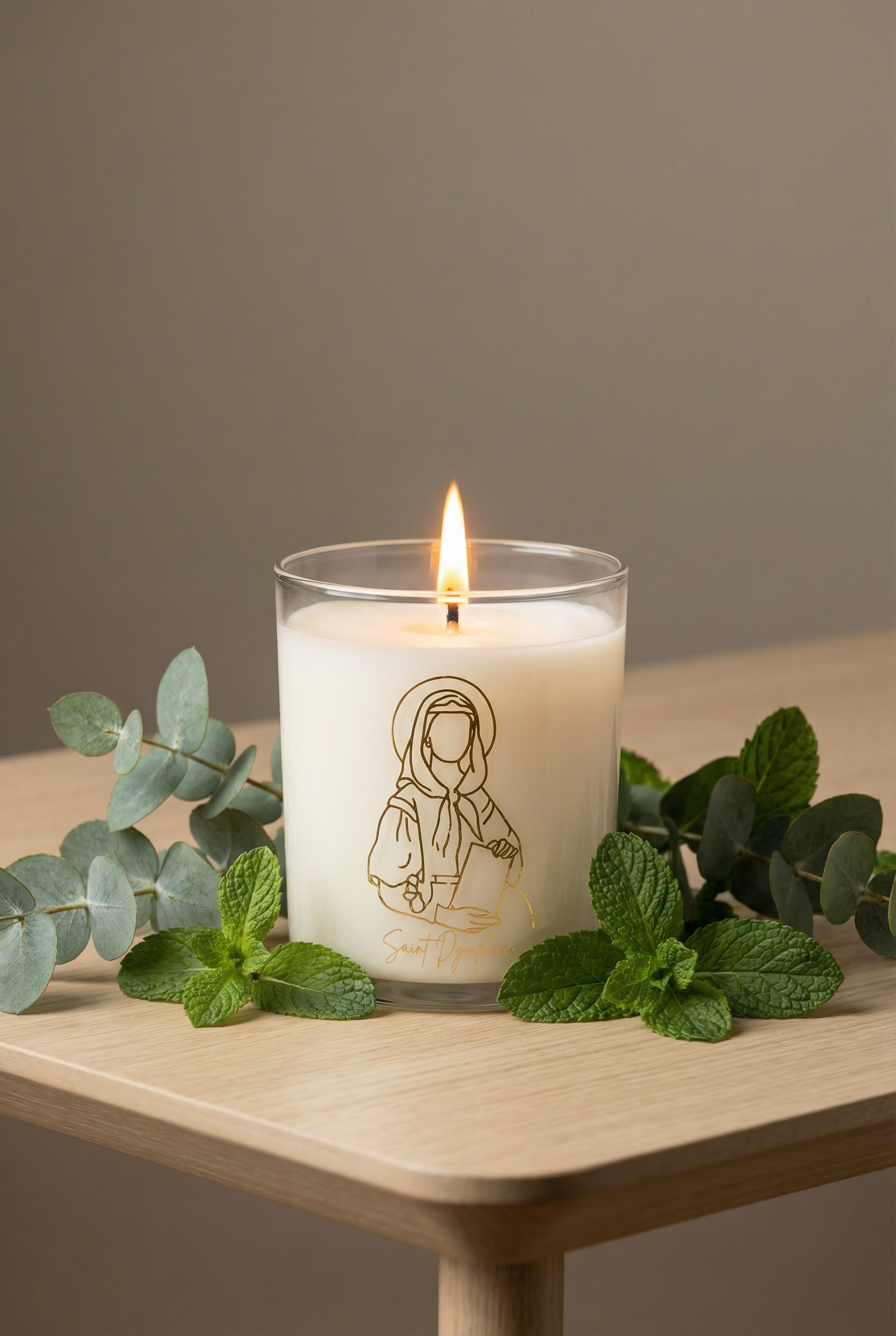 Candle with a figurine design on a wooden surface with green leaves